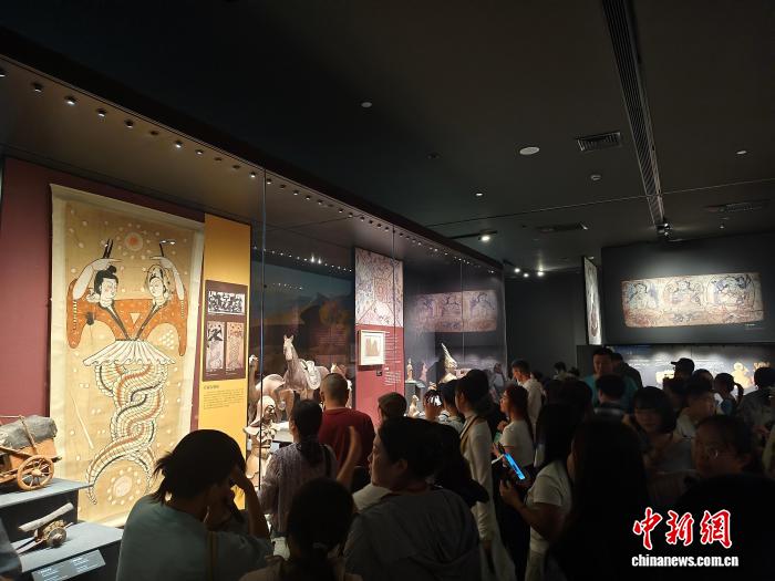 图为台青驻足观看新疆博物馆展出的《伏羲女娲图》。袁鹏冲 摄