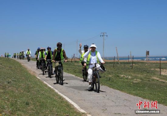 7月5日，青(海)台(湾)学子在青海湖附近骑行，观察青海湖生态环保情况。(青海省海峡两岸交流促进会供图)